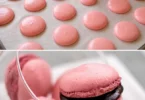 Macarons framboise colorés avec un goût sucré et acidulé, garnis de crème à la framboise.